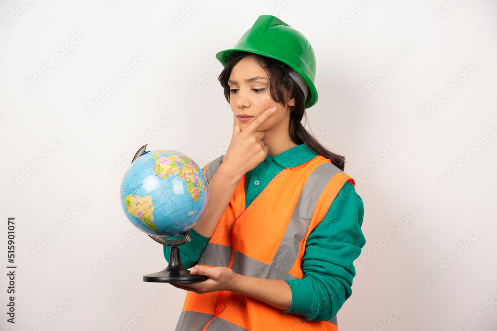 Female firefighter looking at globe with serious expression on white background Female firefighter looking at globe with serious expression on white background