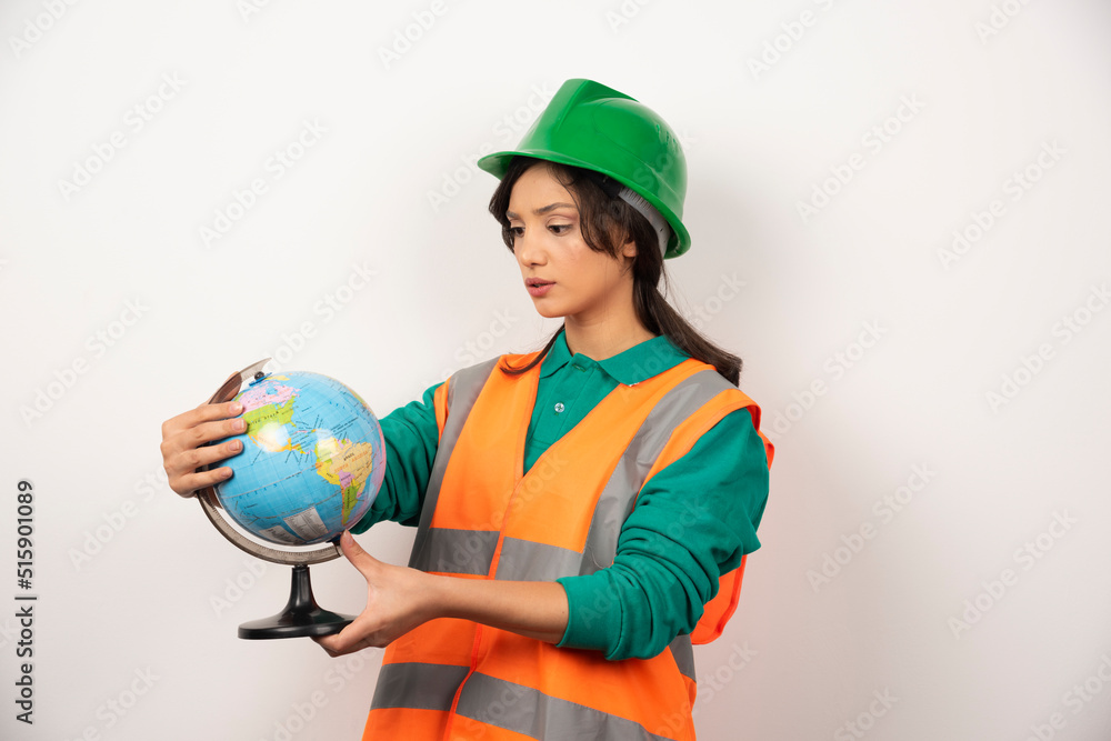 Female firefighter looking at globe with serious expression on white background