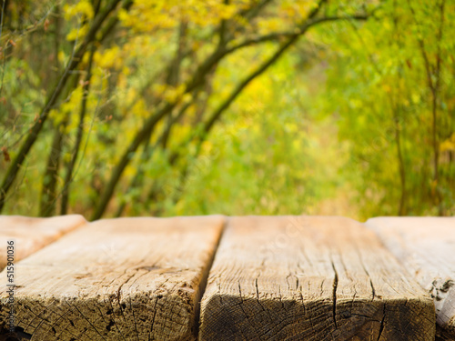 A simple wooden table against the backdrop of autumn nature. Close-up. Minimalism. Family vacation, picnic, lunch in nature. There are no people in the photo. There is free space to insert.