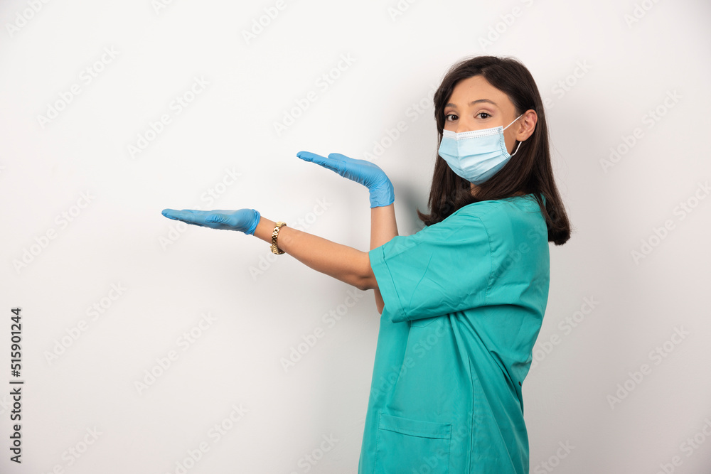 Young doctor in medical mask and gloves standing on white background Young doctor in medical mask and gloves standing on white background