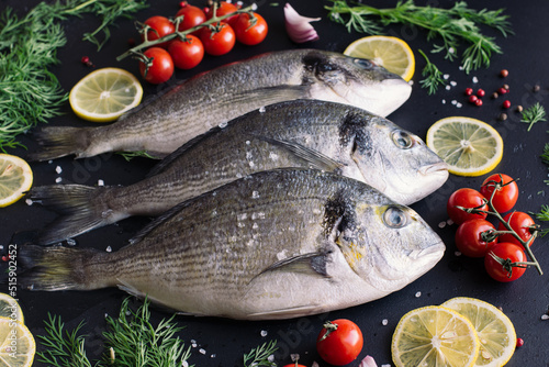 Photography raw dorado fish on black background with herbs and spices