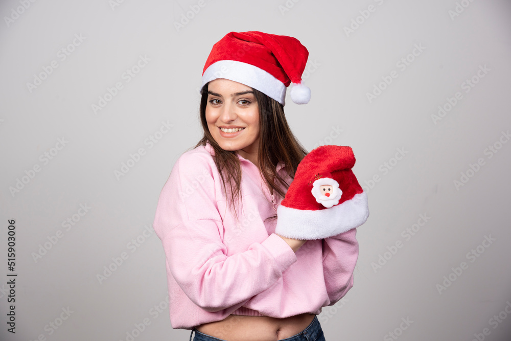 Obraz premium A young woman holding Santa's hats and posing