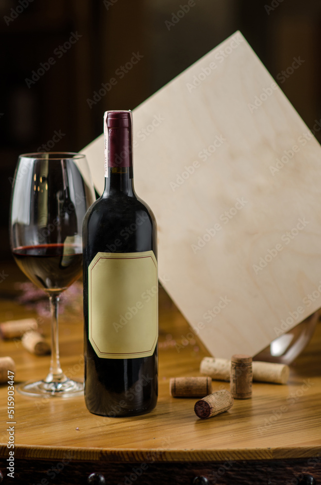 A bottle and a glass of red wine on a wooden table on a wine bar background. Bottle caps on the table. Place for text. Wine bar