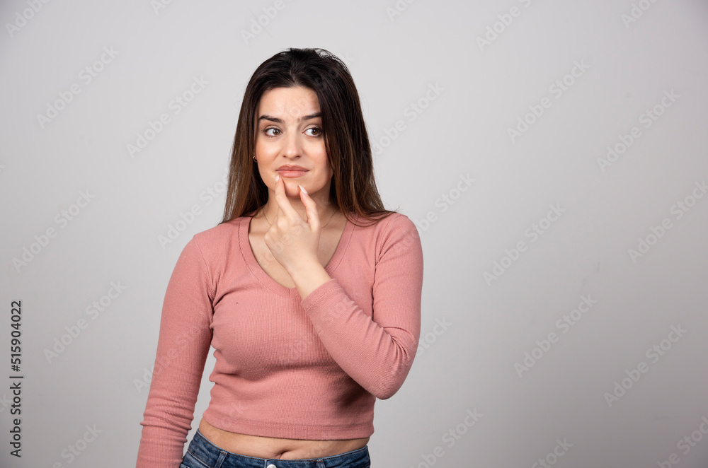 Obraz premium Beautiful young woman with hand near face posing against gray background