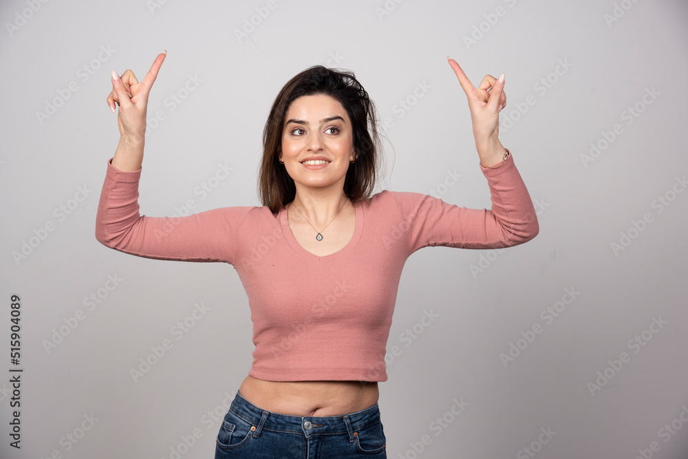 Portrait of a happy young woman pointing fingers up Portrait of a happy young woman pointing fingers up
