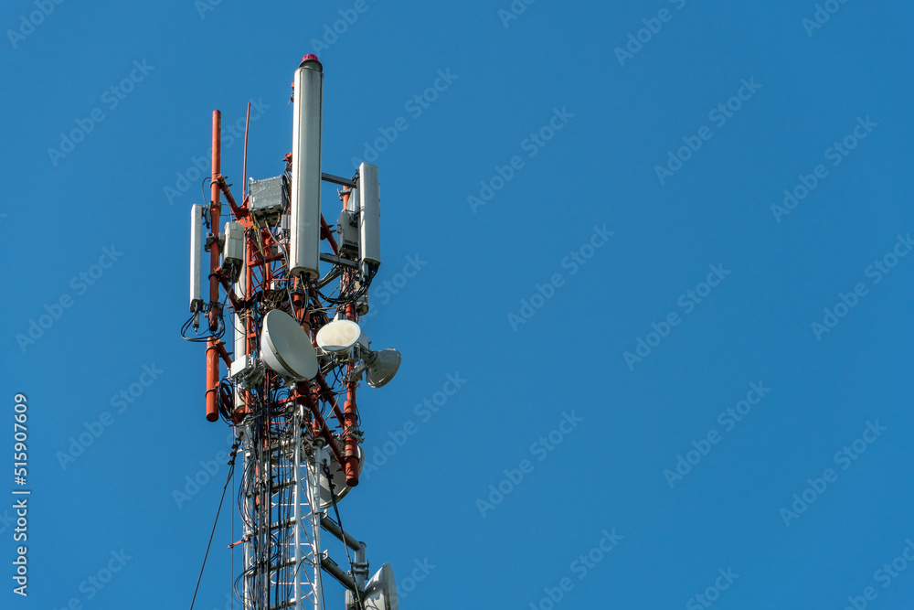 New GSM antennas on a high tower against a blue sky for transmitting a