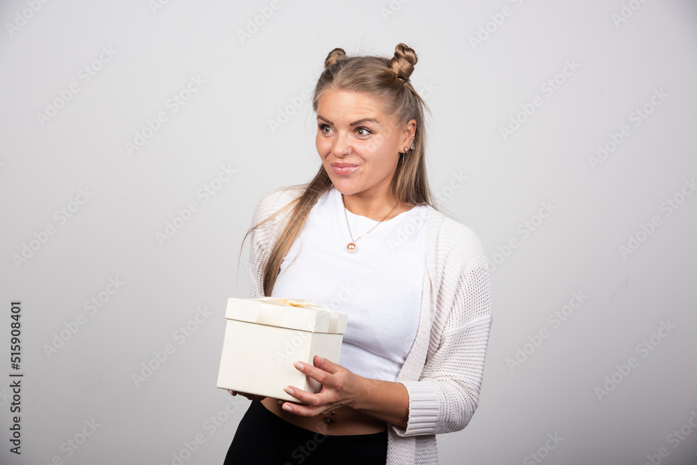 Blonde woman in winter outfit standing with gift box Blonde woman in winter outfit standing with gift box