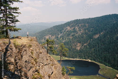 Man looks down over lake in the mountains