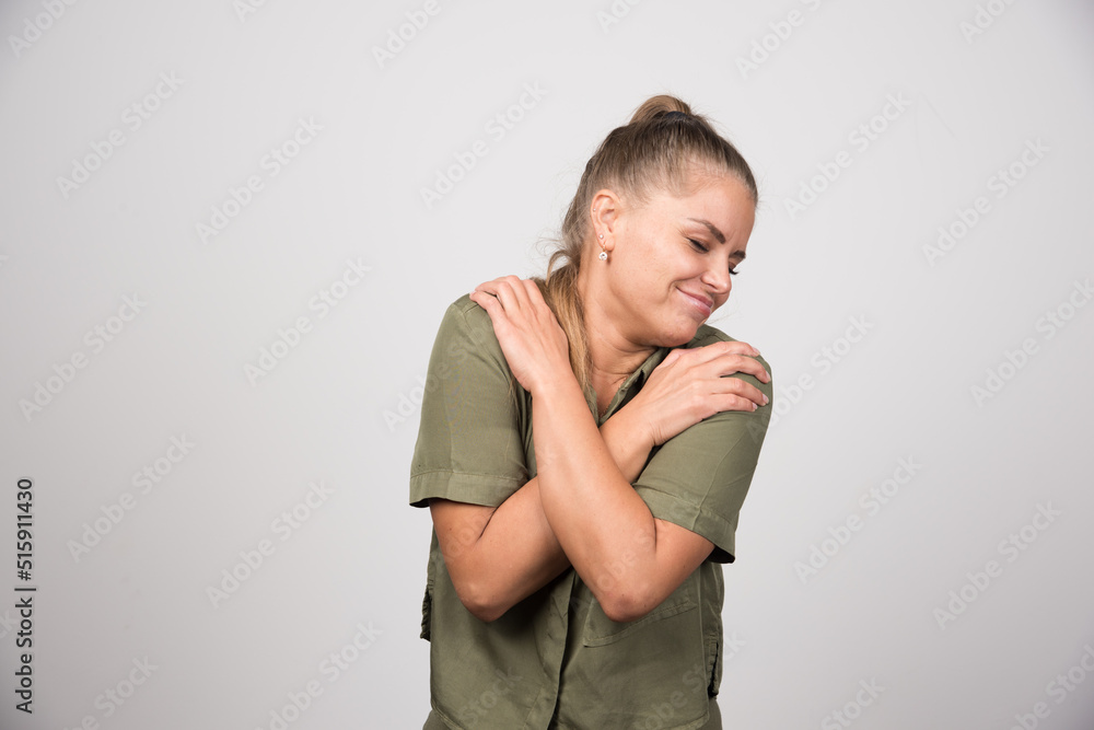 Portrait of woman holding her body on gray background Portrait of woman holding her body on gray background