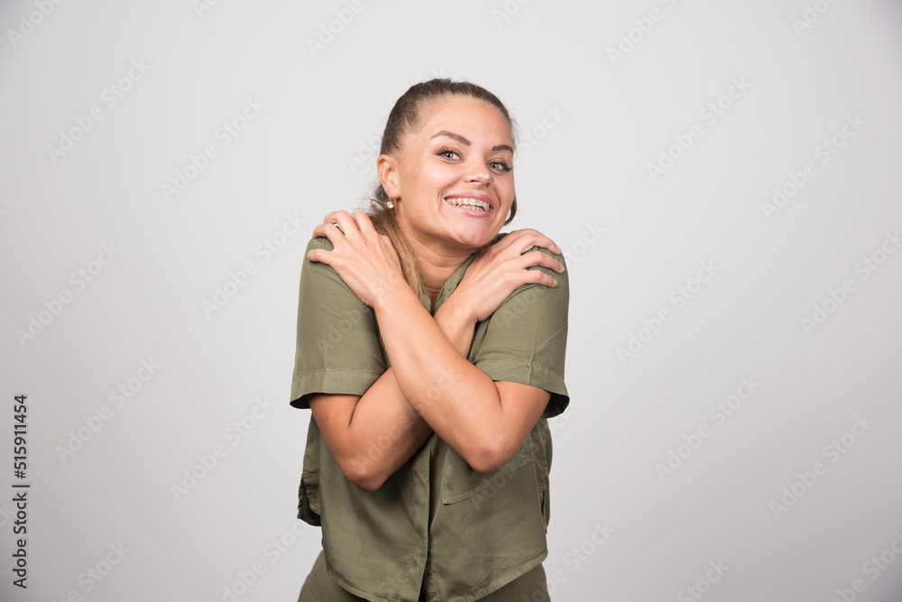 Fototapeta premium Portrait of woman holding her body on gray background