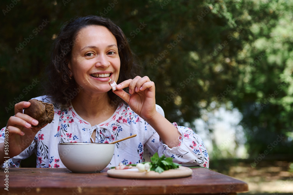 African American woman having lunch outdoors, eating traditional Ukrainian borscht with bacon slice and rye bread African American woman having lunch outdoors, eating traditional Ukrainian borscht with bacon slice and rye bread