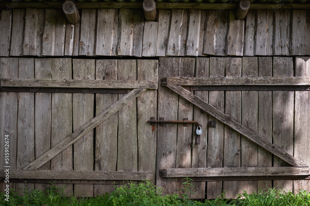 Naklejka premium Old gate made of weathered boards in a rustic barn. Retro background in eco style.