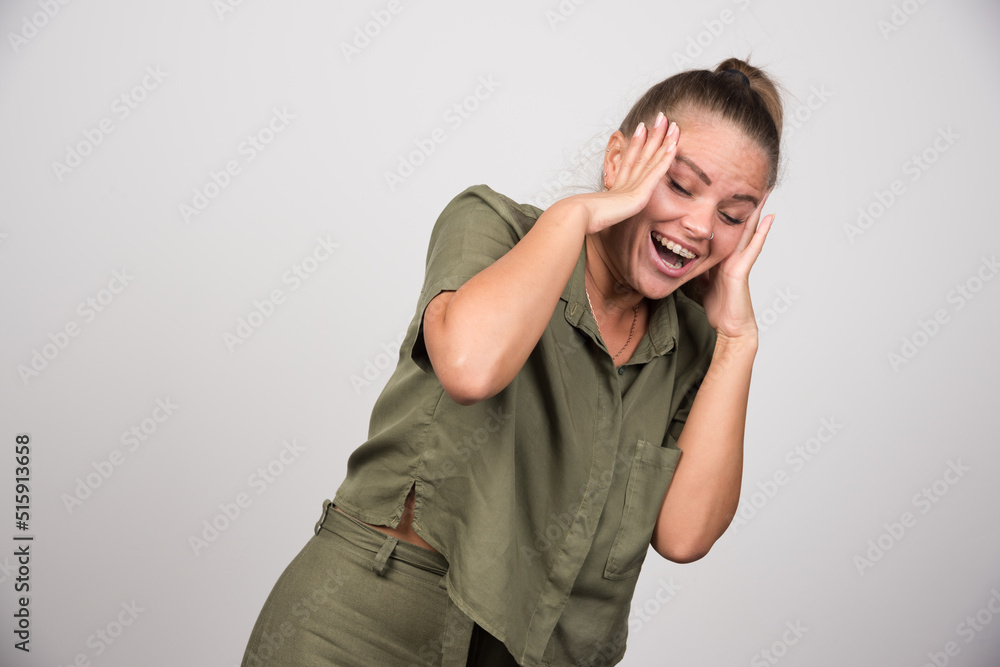 Happy woman holding her head on gray background Happy woman holding her head on gray background