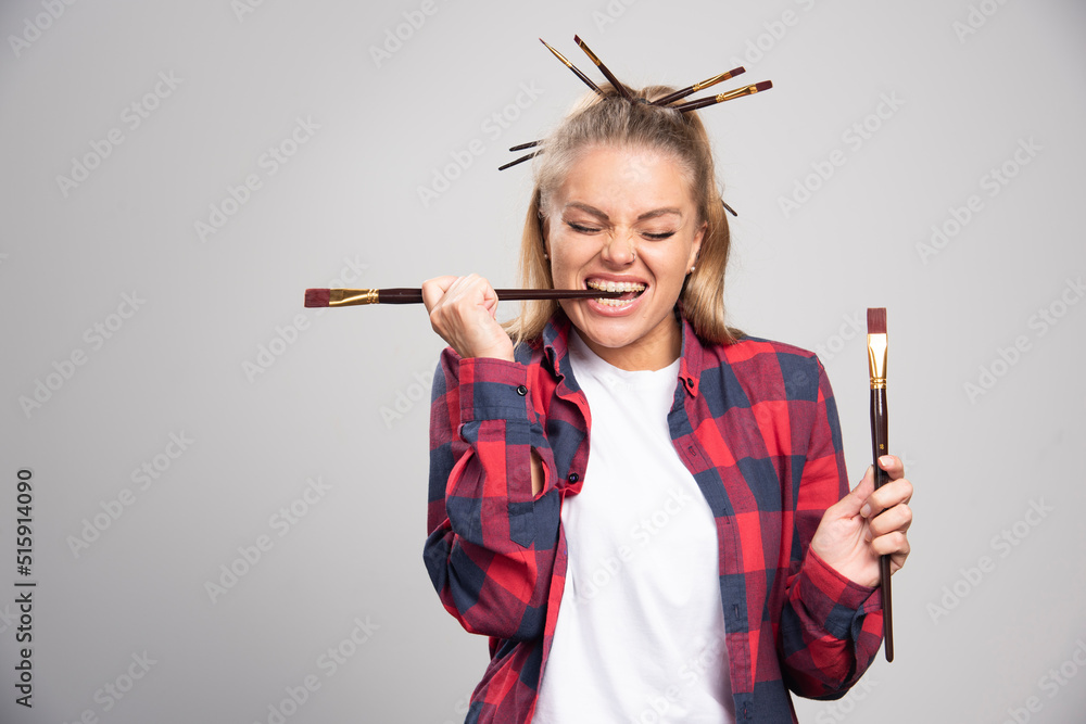 Blonde artist holding brushes, looking at them and having fun Blonde artist holding brushes, looking at them and having fun