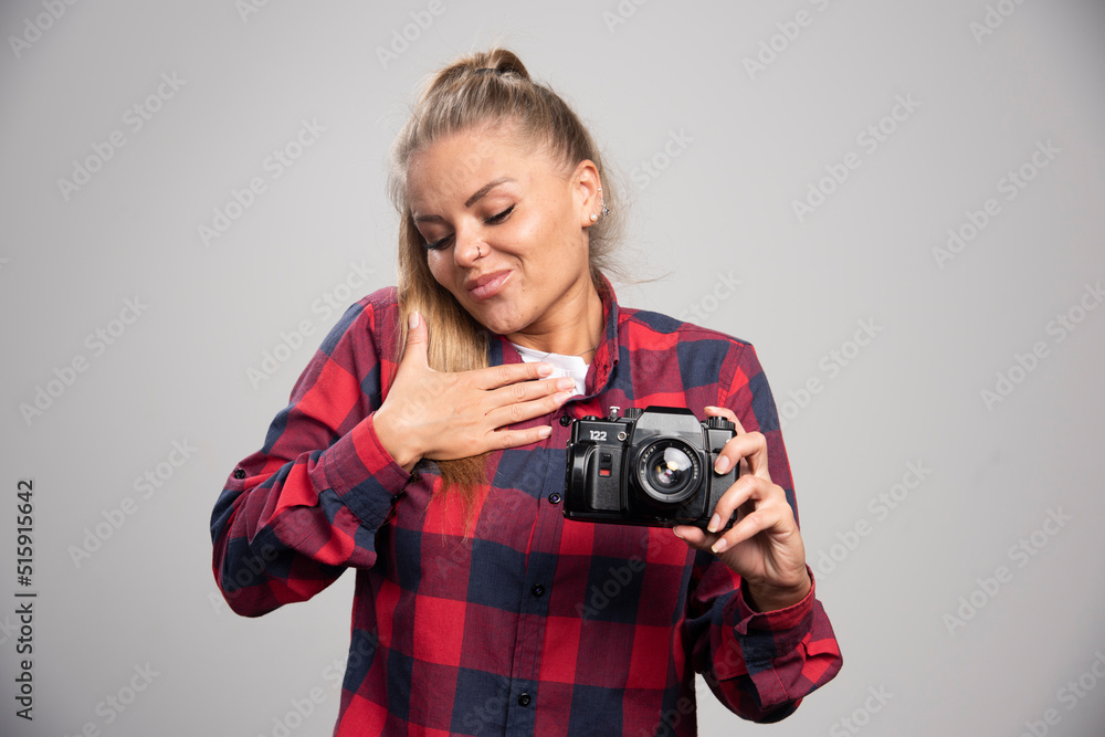 Blonde model in checked shirt with camera points herself Blonde model in checked shirt with camera points herself