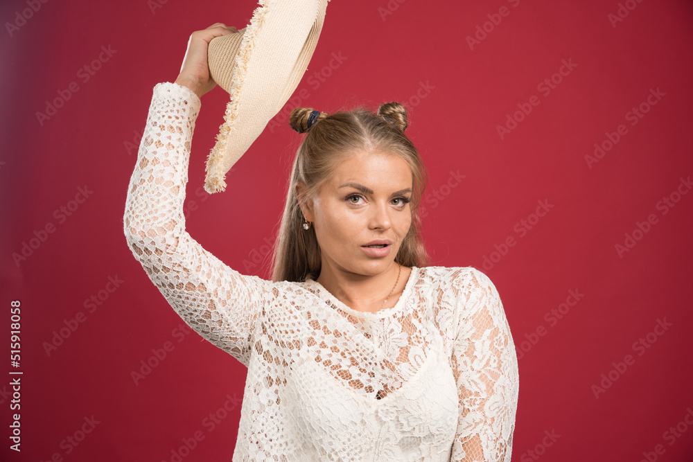 Blonde woman looking front side with hat on red background Blonde woman looking front side with hat on red background