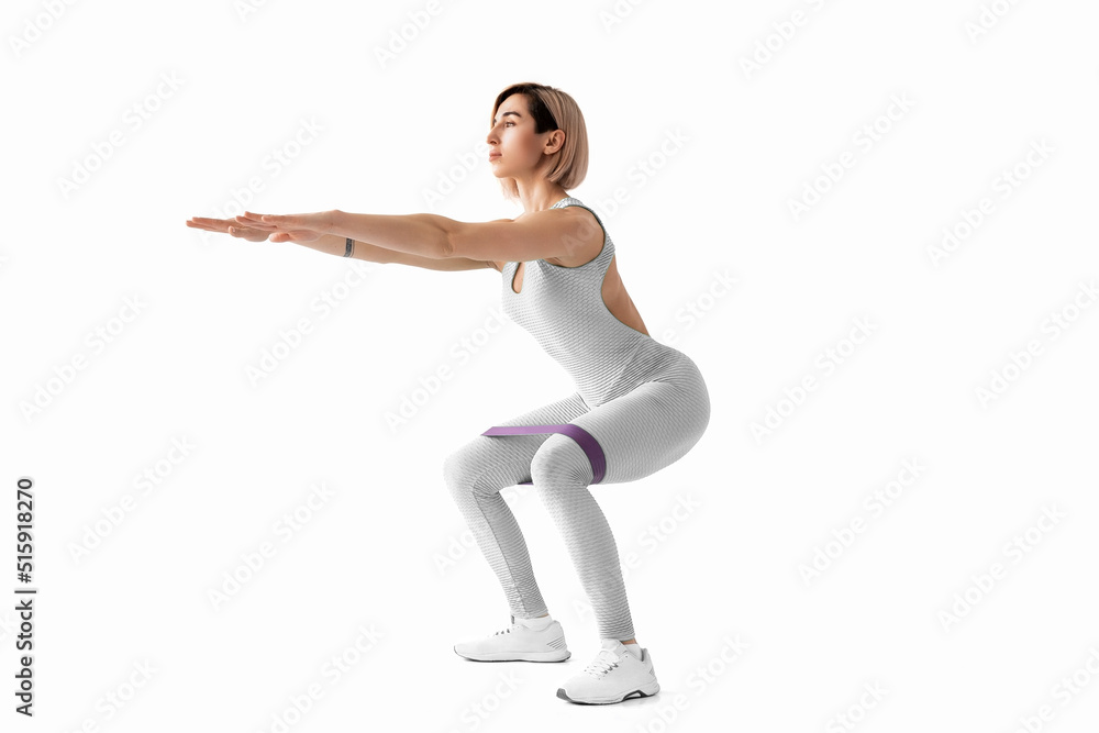 Sexy woman in sportswear using a resistance band in her exercise routine. Young woman performs fitness exercises on white background. Isolate Sexy woman in sportswear using a resistance band in her exercise routine. Young woman performs fitness exercises on white background. Isolate
