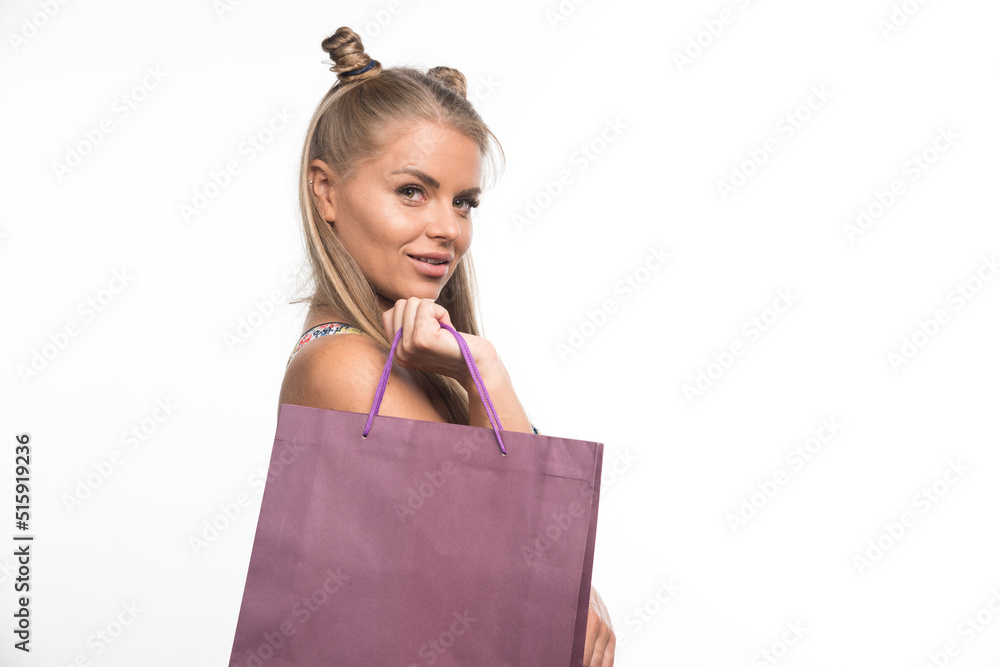 Blonde woman looking aside and carrying her shopping bags on white background Blonde woman looking aside and carrying her shopping bags on white background
