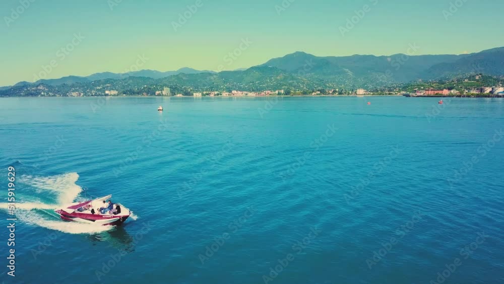 Aerial view of beautiful boats and yachts on Black Sea coast in Batumi Georgia in blue sea. Landscape with yacht, mountains, clear blue water, top view of boat. Aerial view of high-speed tourist boat Aerial view of beautiful boats and yachts on Black Sea coast in Batumi Georgia in blue sea. Landscape with yacht, mountains, clear blue water, top view of boat. Aerial view of high-speed tourist boat