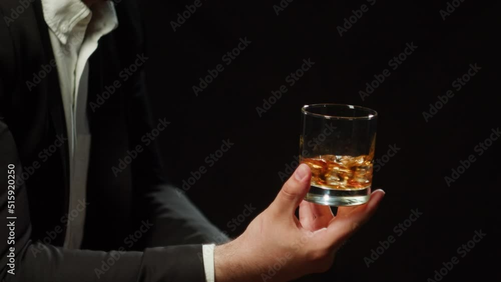 Drinking brandy or whiskey close-up. Rich man drinks luxury cognac on black background. Alcohol amber rum, liqour beverage in glass. Drinking brandy or whiskey close-up. Rich man drinks luxury cognac on black background. Alcohol amber rum, liqour beverage in glass.