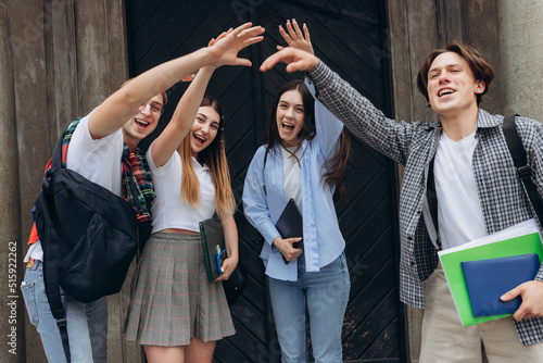 Group of students standing in a circle with hands raised in the air
