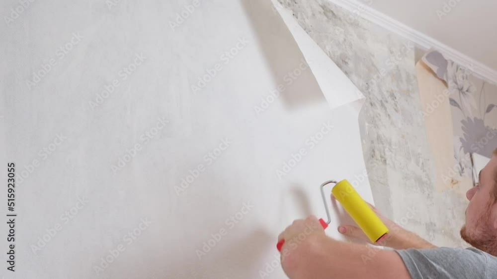 A man rolls out a canvas of white wallpaper with a suture wallpaper