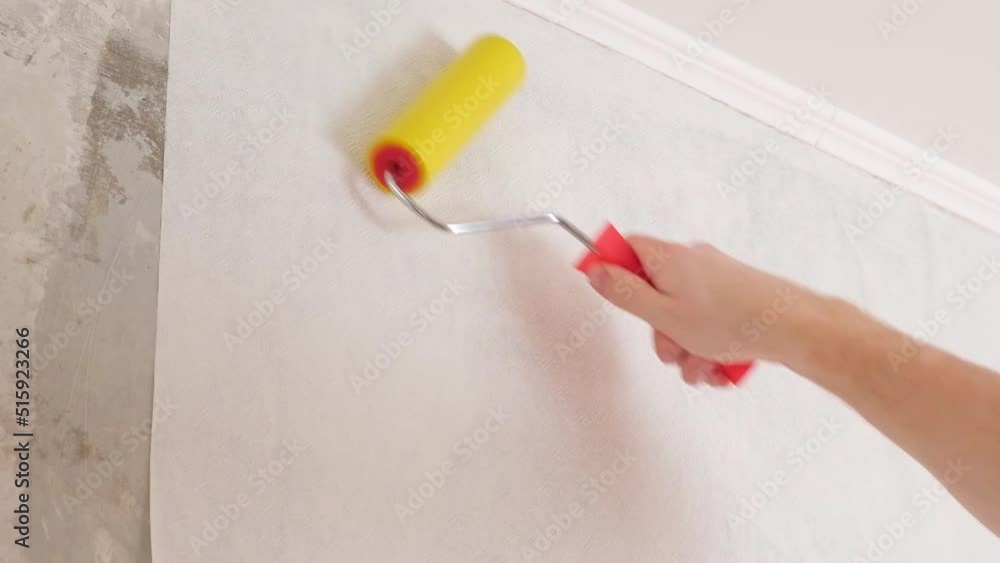 Video Stock A man rolls out a canvas of white wallpaper with a suture wallpaper yellow roller