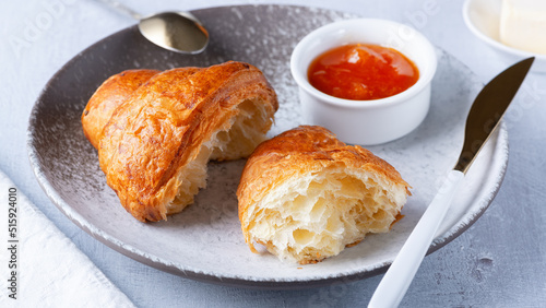 A freshly baked French Croissant, butter and jam.