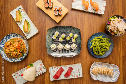 set of asian food dishes with sushi, avocado maki, shrimp noodles, edamame beans, gyozas, norwegian salmon and bao bread photo