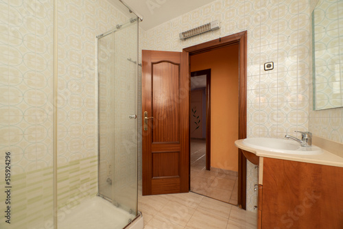 Bathroom with wooden furniture  glass shower cubicle and dark wooden doors