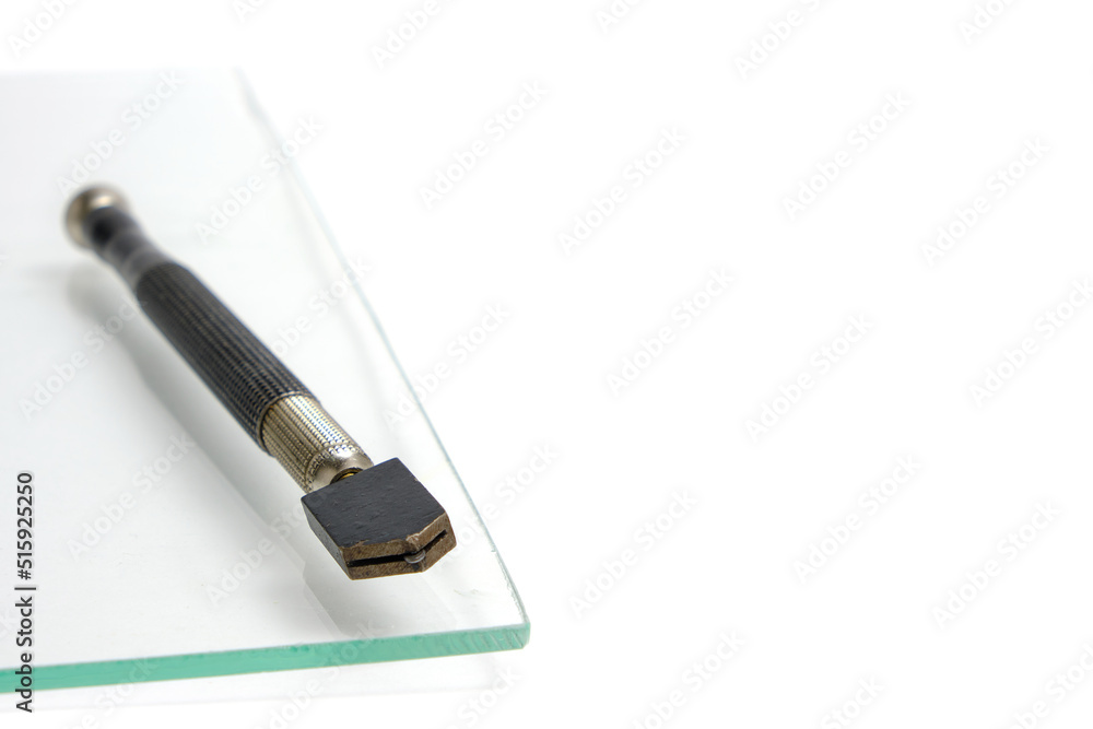 Piece of glass and manual glass cutter white background.