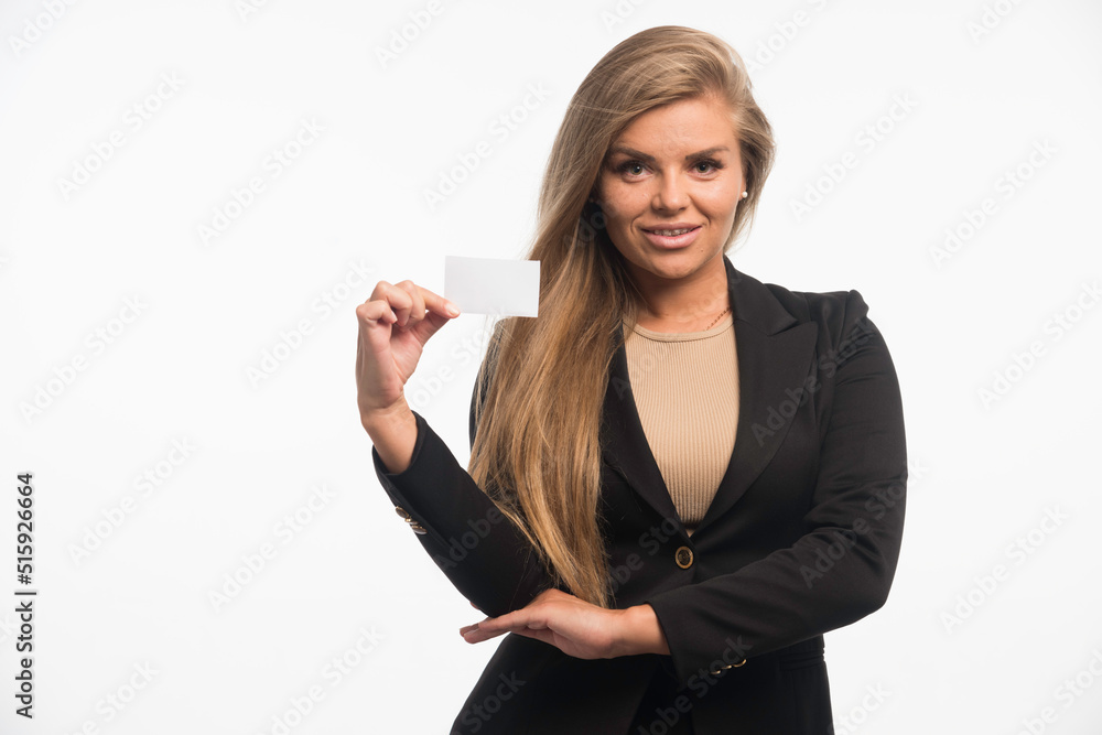 Young businesswoman in black suit checking business card of the customer and smiling Young businesswoman in black suit checking business card of the customer and smiling