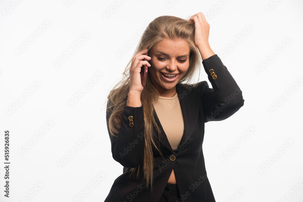Young businesswoman in black suit putting her hand to her head while talking to phone Young businesswoman in black suit putting her hand to her head while talking to phone