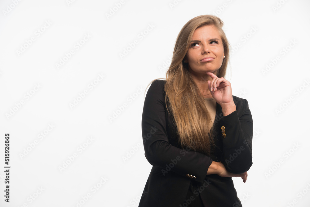 Young businesswoman in black suit looking up and thinking Young businesswoman in black suit looking up and thinking