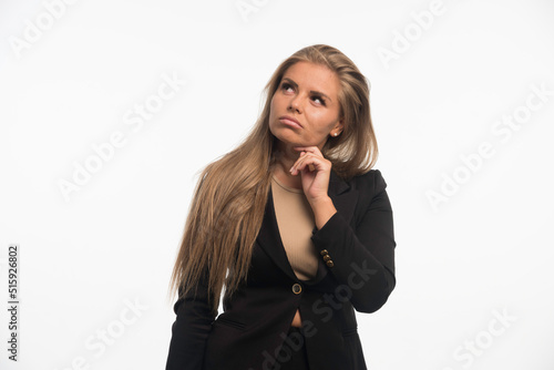 Young businesswoman in black suit looks doubtful