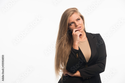Young businesswoman in black suit looking up and thinking