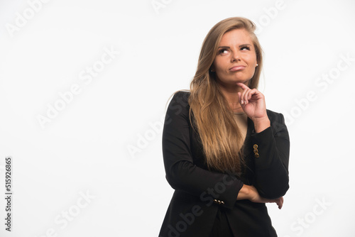 Young businesswoman in black suit looking up and thinking