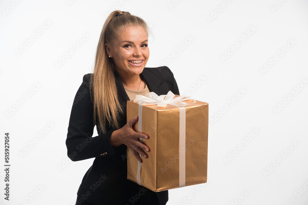 Young businesswoman in black suit looks to a gift box and looks excited Young businesswoman in black suit looks to a gift box and looks excited