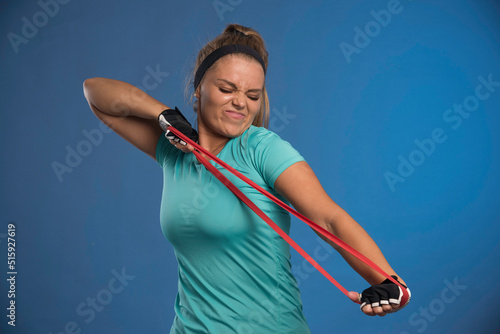 Young sportive woman stretching her arm muscles and looks strengthless photo