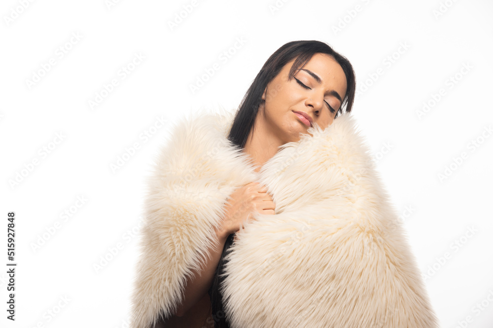 Portrait of young woman posing with fur coat on white background Portrait of young woman posing with fur coat on white background