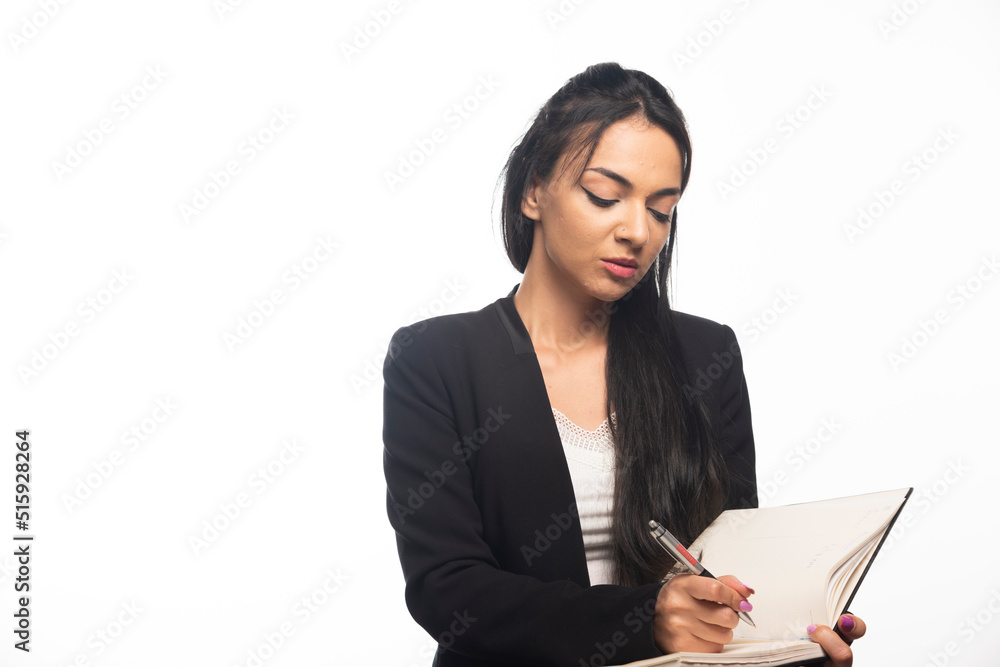 Portrait of young businesswoman writing in notebook with pen Portrait of young businesswoman writing in notebook with pen