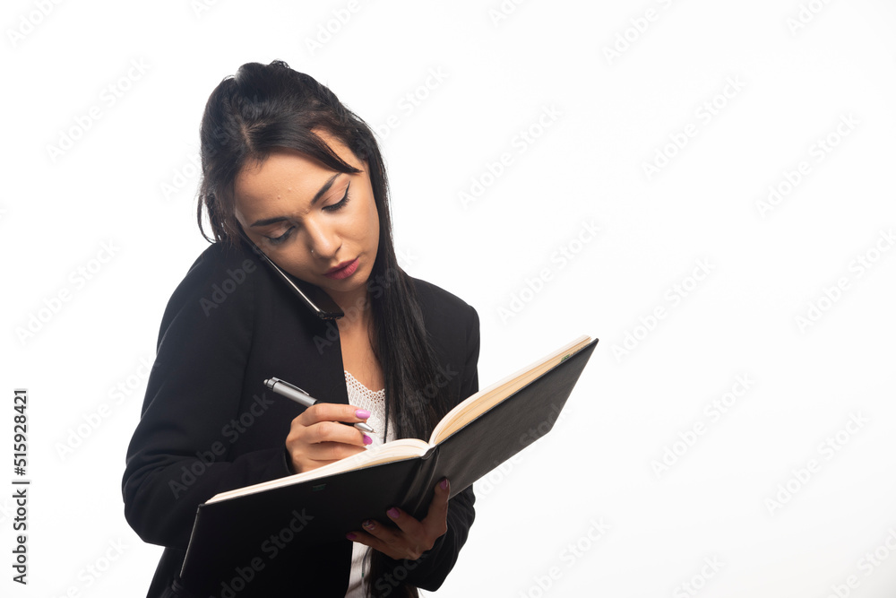 Business woman writing in notebook with pencil on white background Business woman writing in notebook with pencil on white background