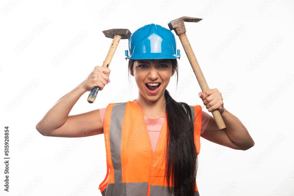 Woman wearing in vest and helmet holding hammers Woman wearing in vest and helmet holding hammers