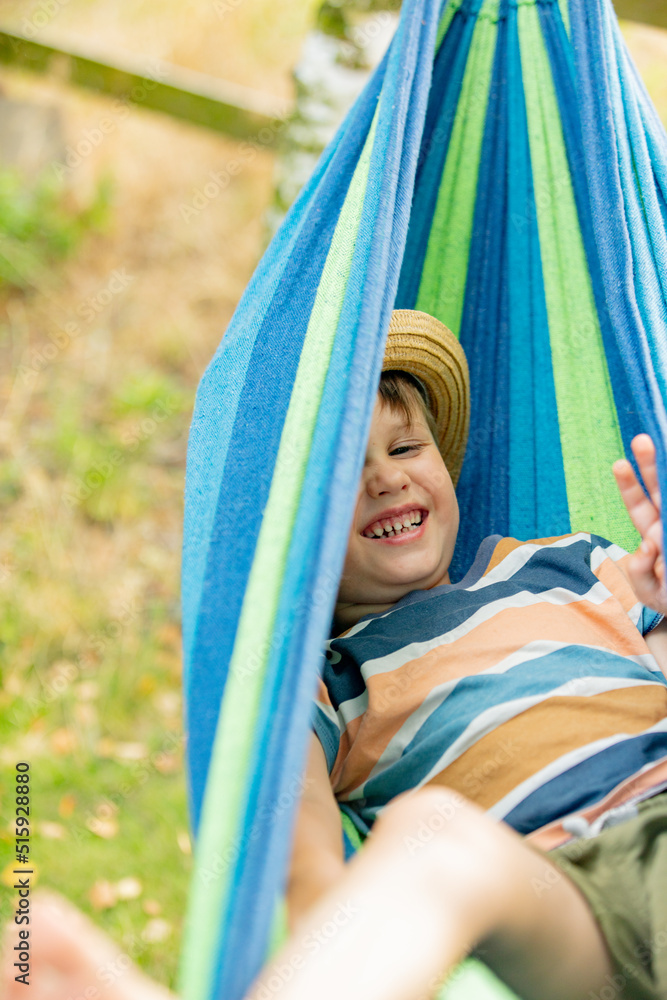 Happy kid boy in hammock in summer garden Happy kid boy in hammock in summer garden
