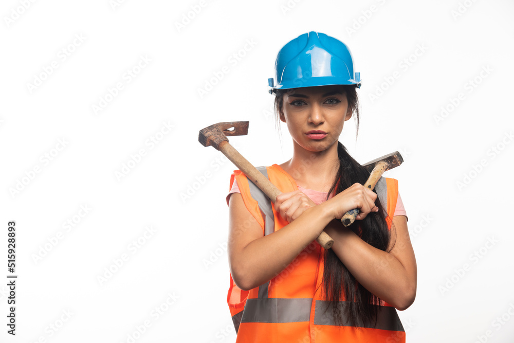 Woman wearing in vest and helmet holding hammers