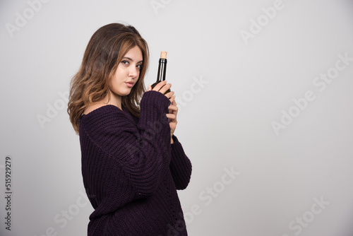 Young woman in warm knitted sweater holding a bottle of wine