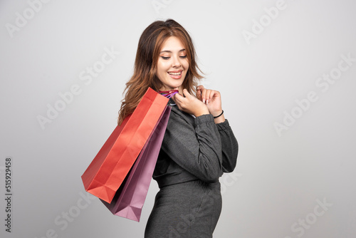 Image of a beautiful young woman posing isolated over gray wall background holding shopping bags