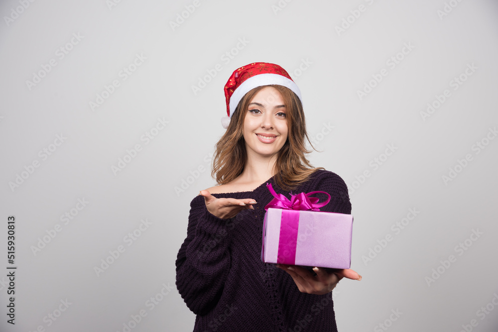 Young woman in Santa hat showing a gift box present Young woman in Santa hat showing a gift box present
