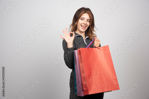 Photo of young woman with shopping bags and waving hand