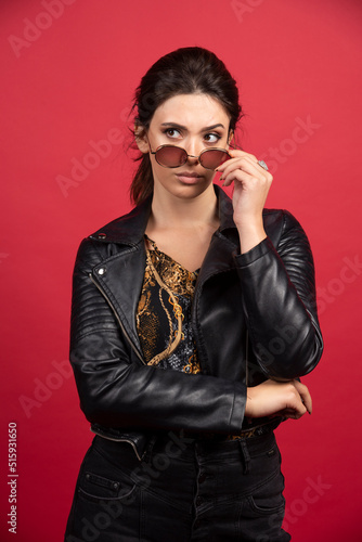Cool girl in black leather jacket taking out her sunglasses and smiling
